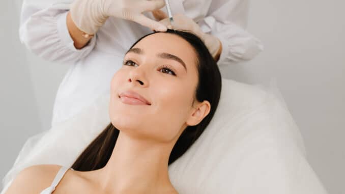 PRP Behandlung der Haare bei einer Frau: Ärztliches Fachpersonal injiziert plättchenreiches Plasma in die Kopfhaut